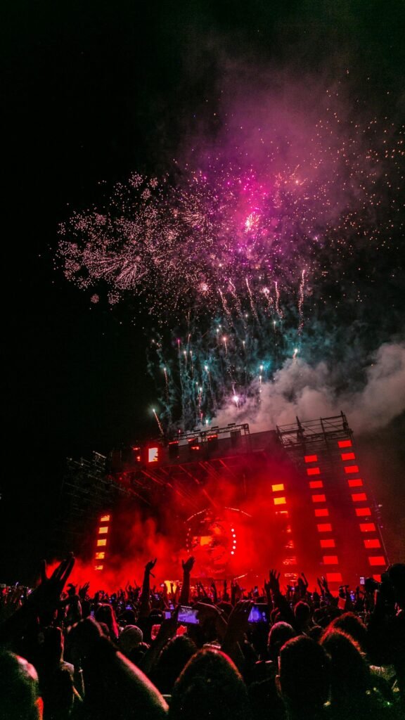 Energetic outdoor concert at night with a vibrant fireworks display and crowd enjoying live music.